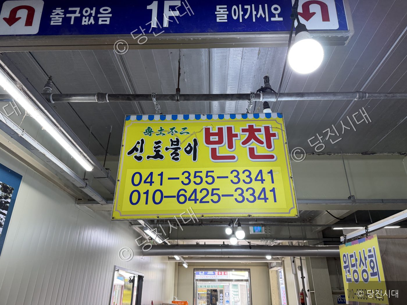 실내 시장에 반찬 가게 안내 표지판이 걸려 있다.