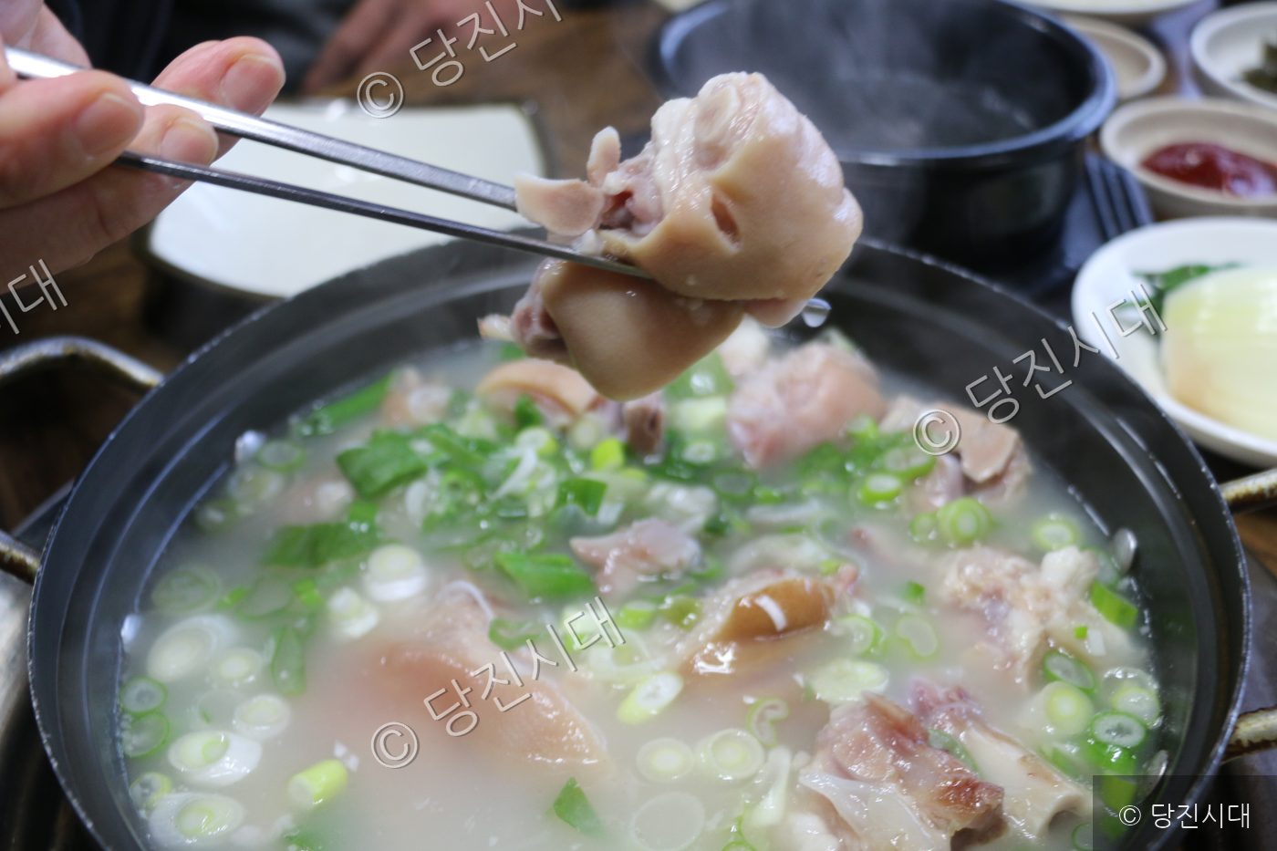 식당에서 손님이 족탕의 고기를 집어 들고 있다.