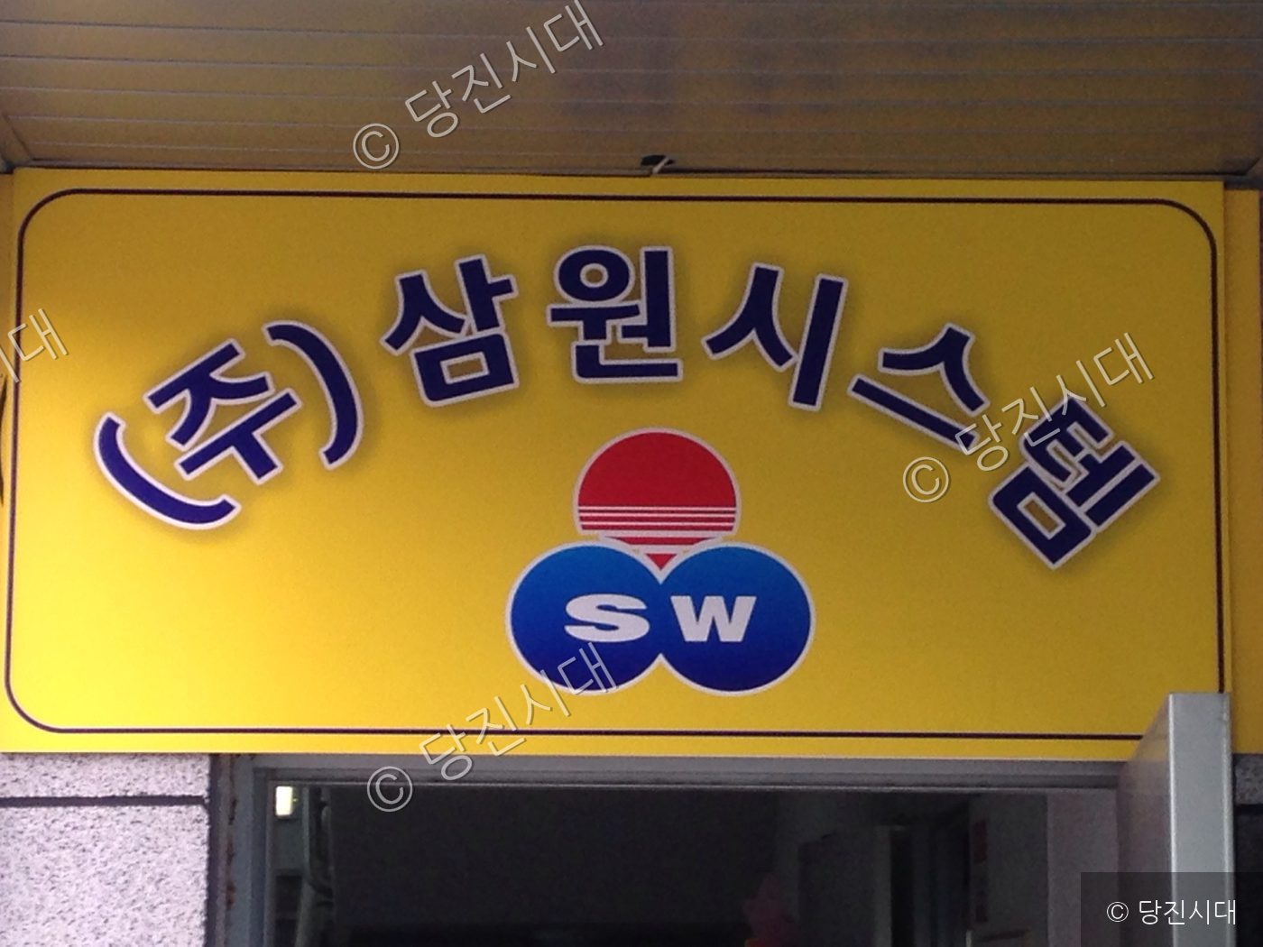 신설 상가인 삼원시스템의 간판이 건물 입구 위에 부착되어 있다.