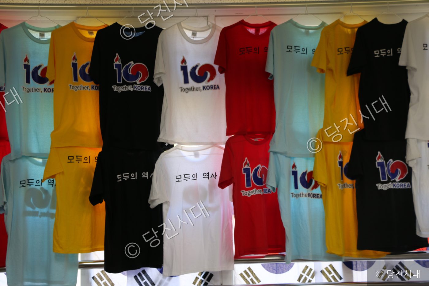 행사를 기념하는 다양한 색상의 티셔츠들이 걸려 있다.
