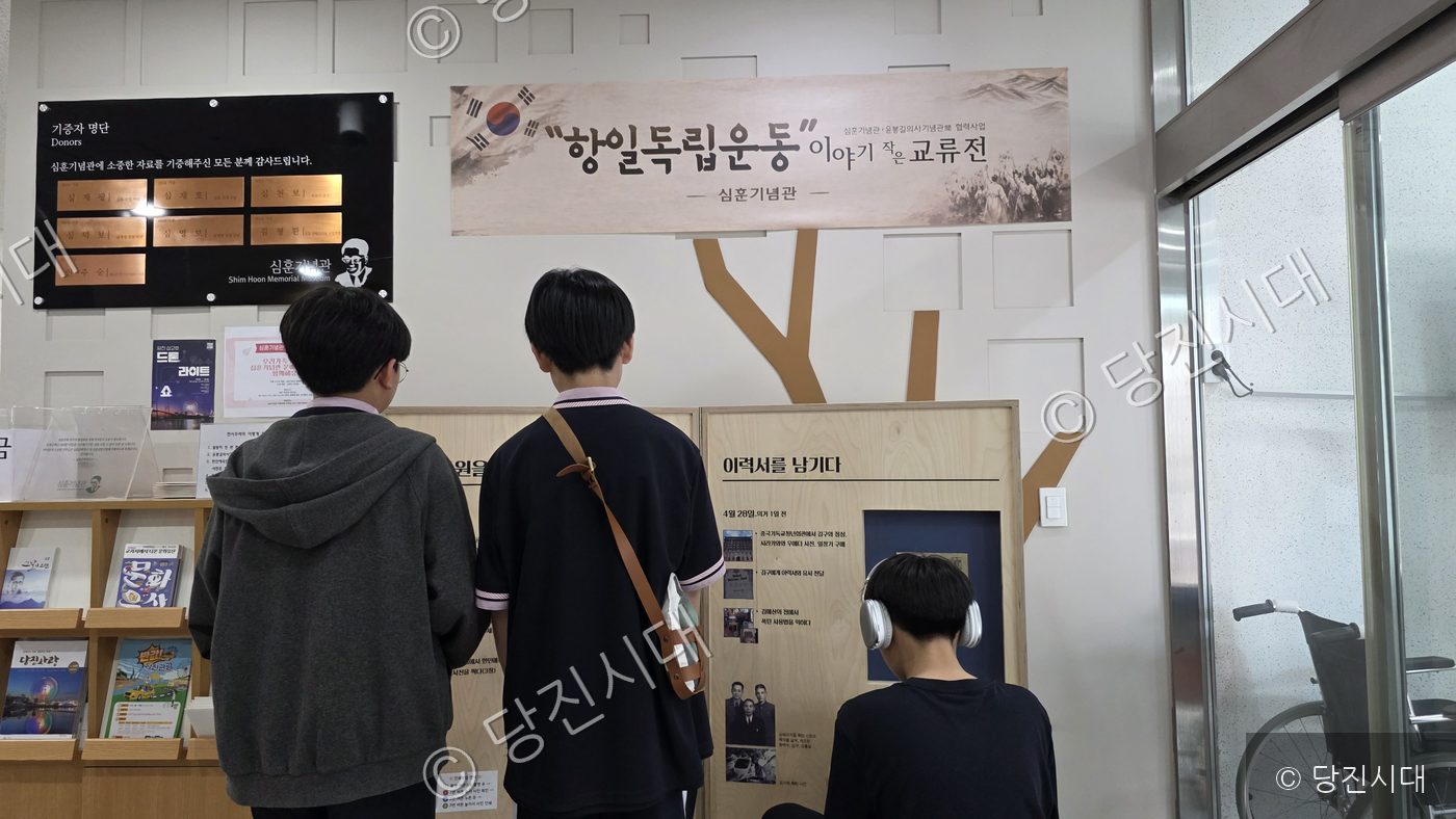 세 명의 학생이 심훈기념관 전시물을 관람하고 있다.