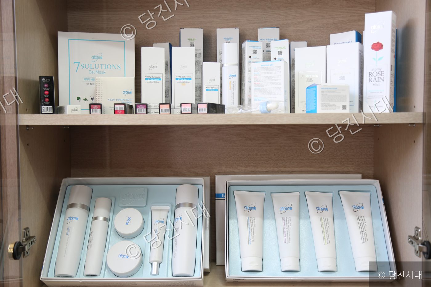 수납장에 아토미 화장품 세트와 제품들이 진열되어 있다.