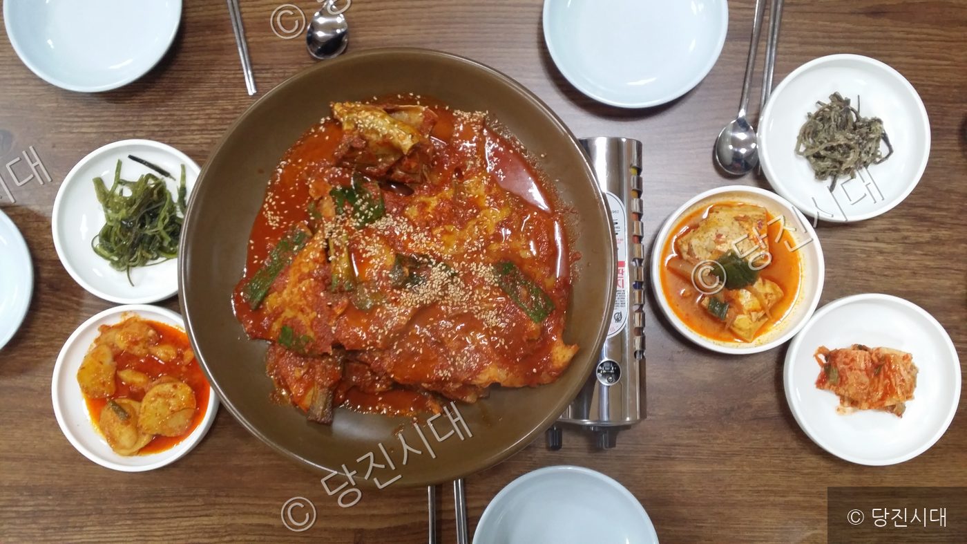 당진의 한 식당에서 붉은 양념의 생선찜과 여러 밑반찬이 차려져 있다.