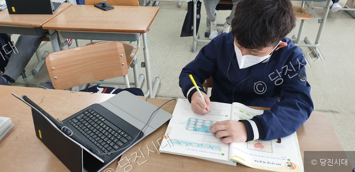 한 학생이 교실에서 태블릿을 보며 공부하고 있다.