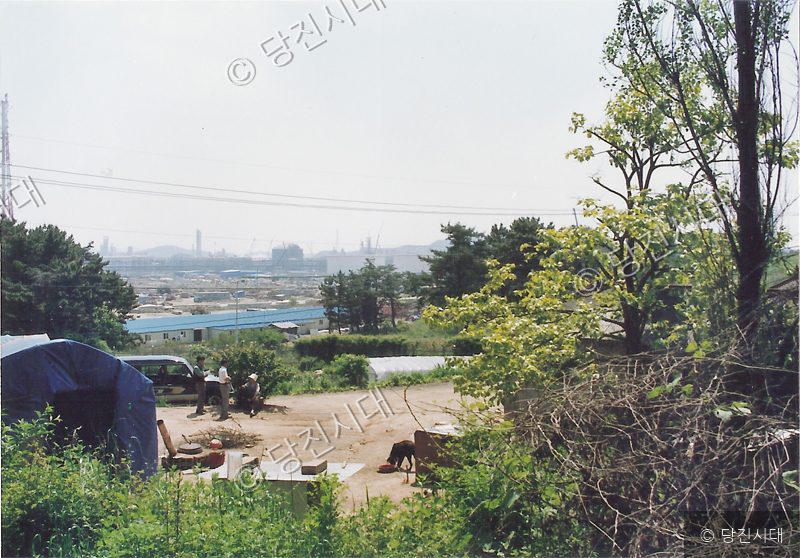 당진 지역의 한 주택가 풍경과 멀리 보이는 산업단지 모습.