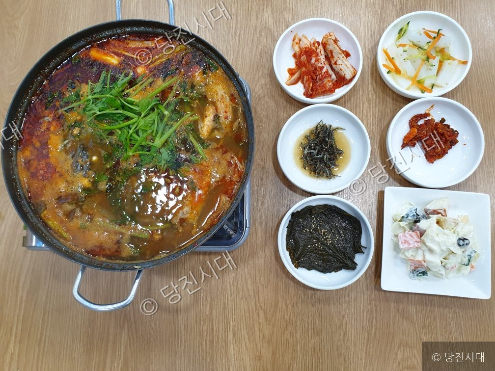 싱싱횟집의 매운탕과 다양한 밑반찬이 식탁 위에 차려져 있다.