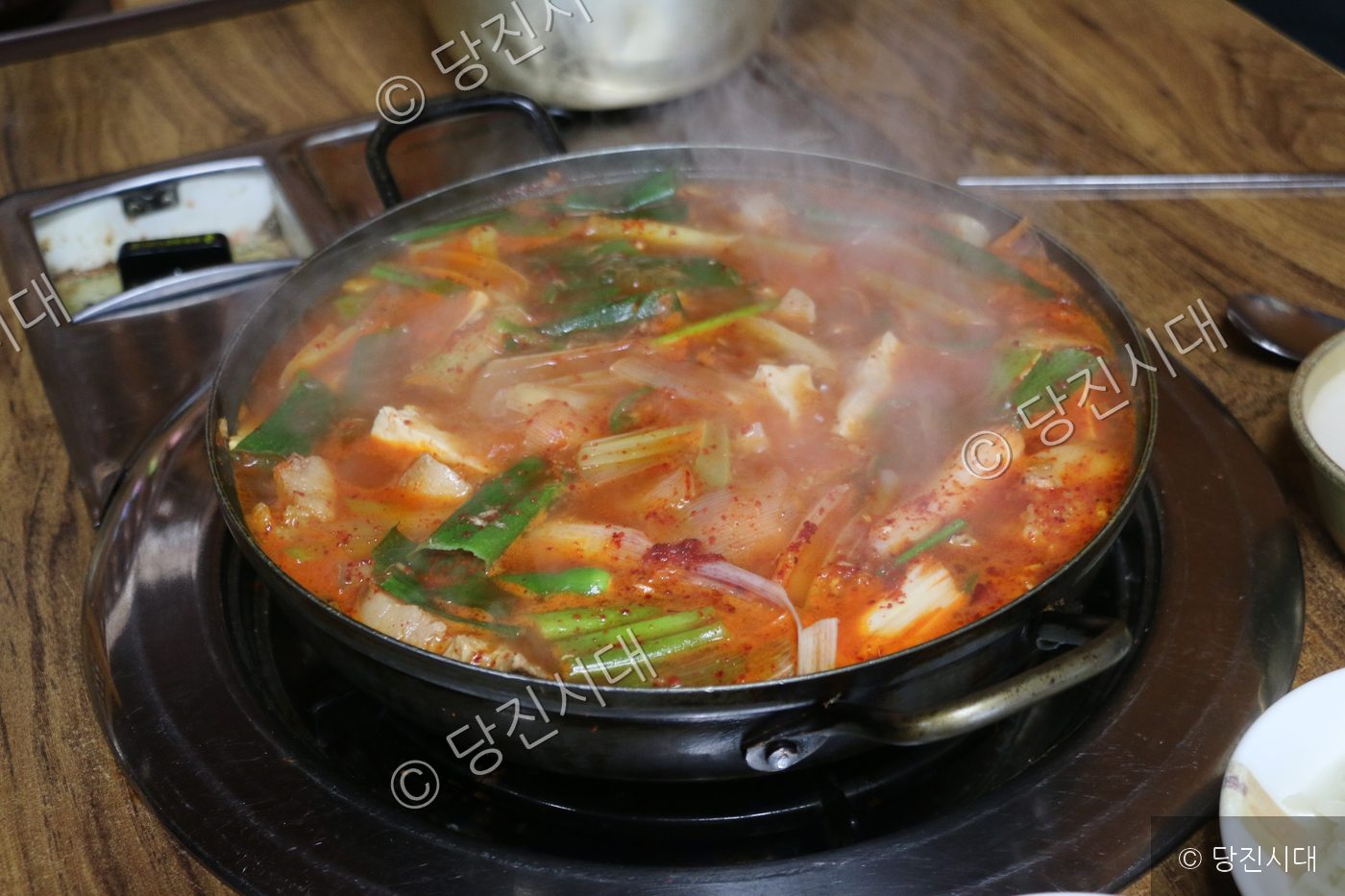 식당 테이블에서 김치찌개가 뜨겁게 끓고 있다.