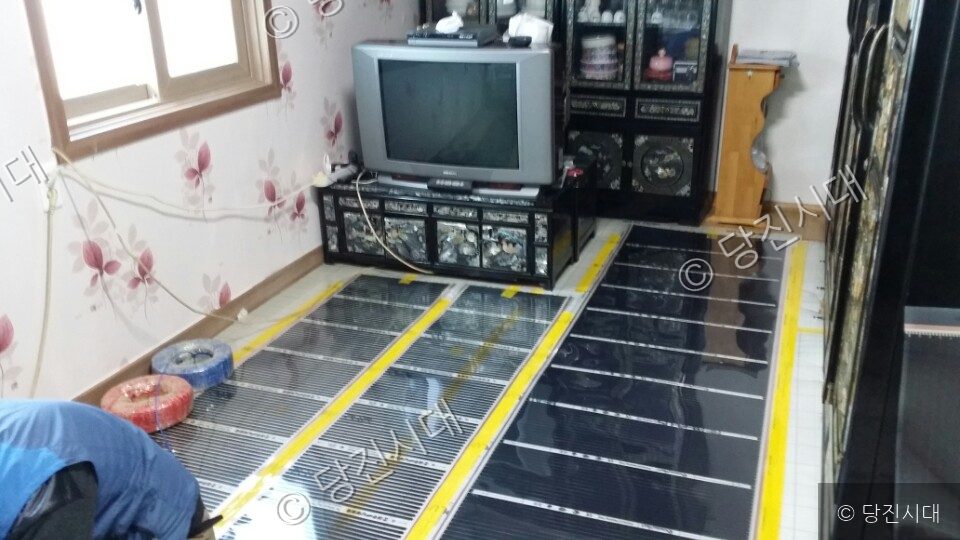 실내 바닥에 난방 필름을 설치하고 있다.