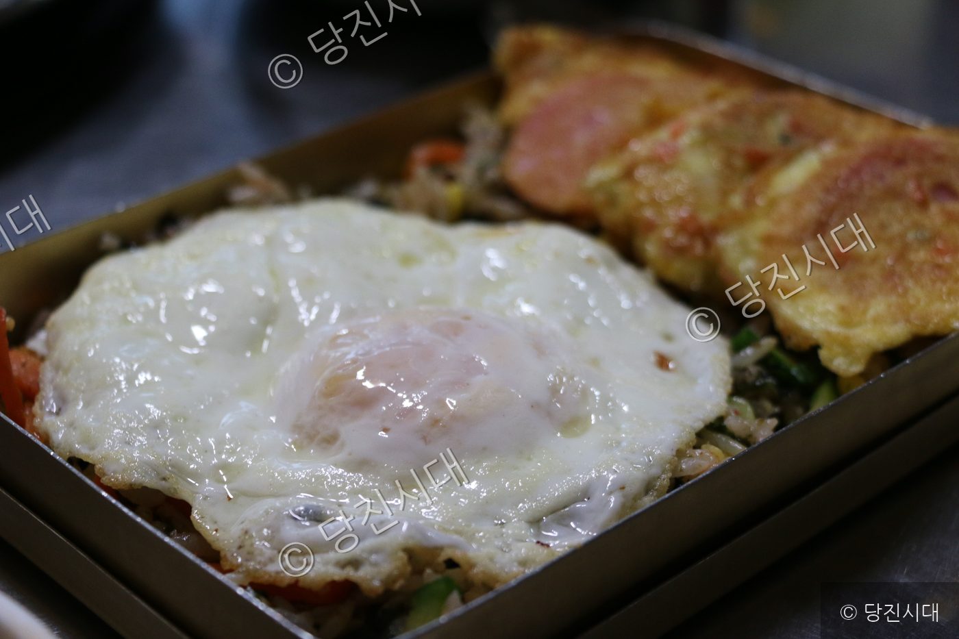 도시락에 계란후라이와 반찬이 담겨 있다.