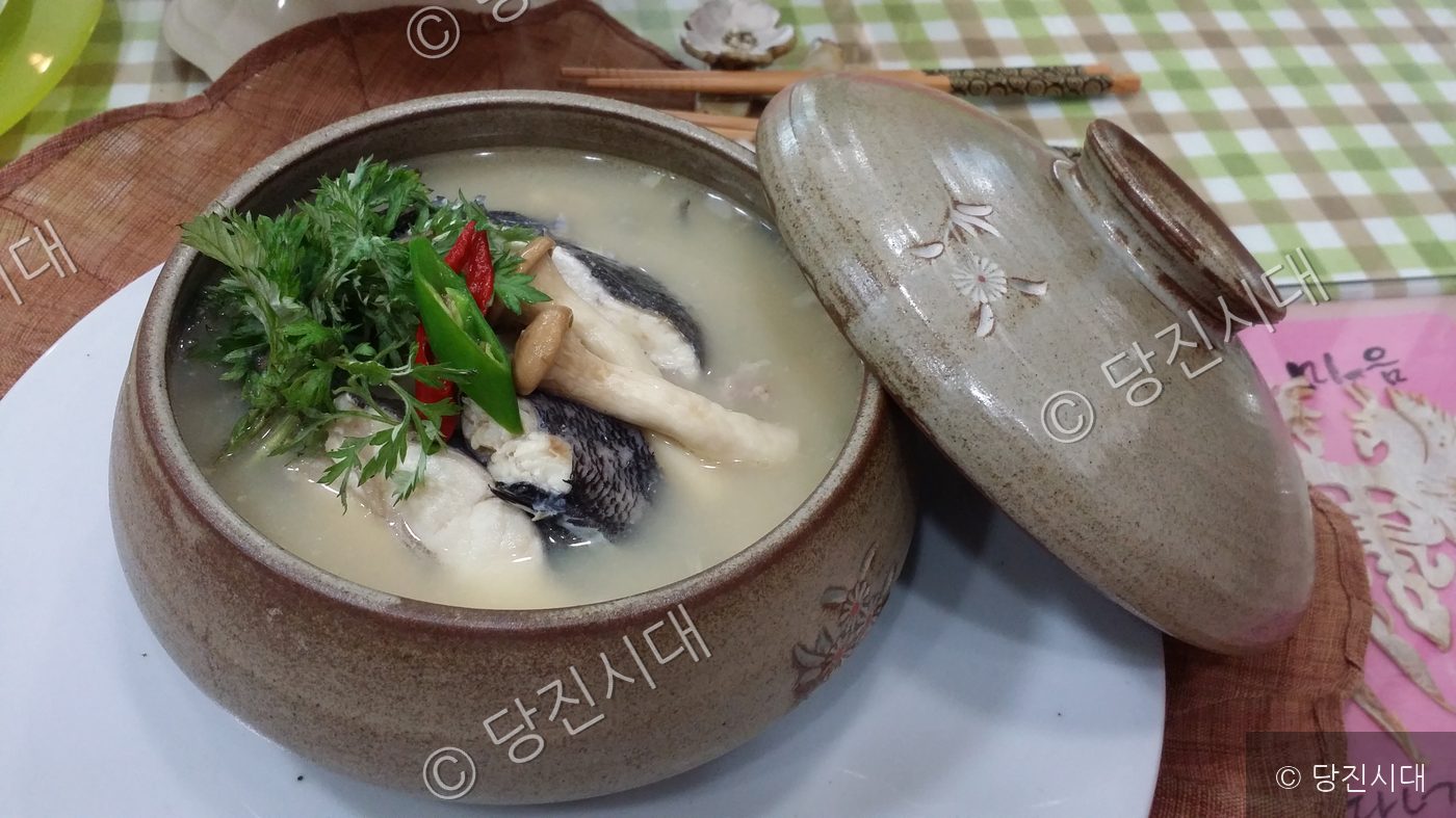 그릇에 담긴 따뜻한 우럭쑥국이 놓여 있다.