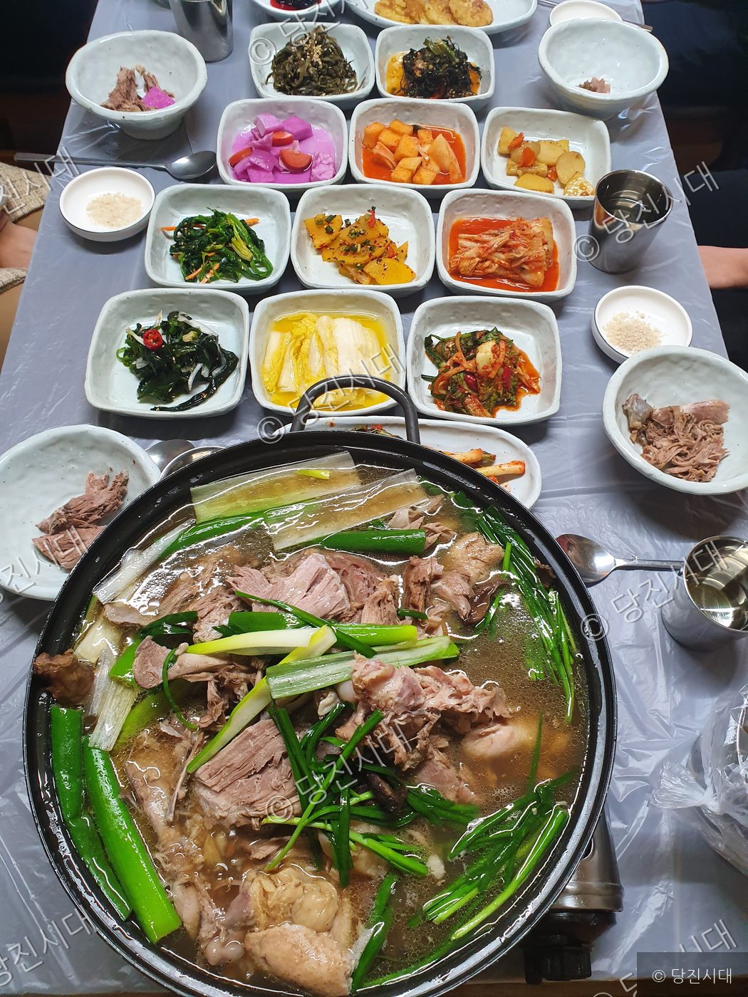 식탁 위에 능이버섯 백숙과 여러 가지 반찬들이 차려져 있다.