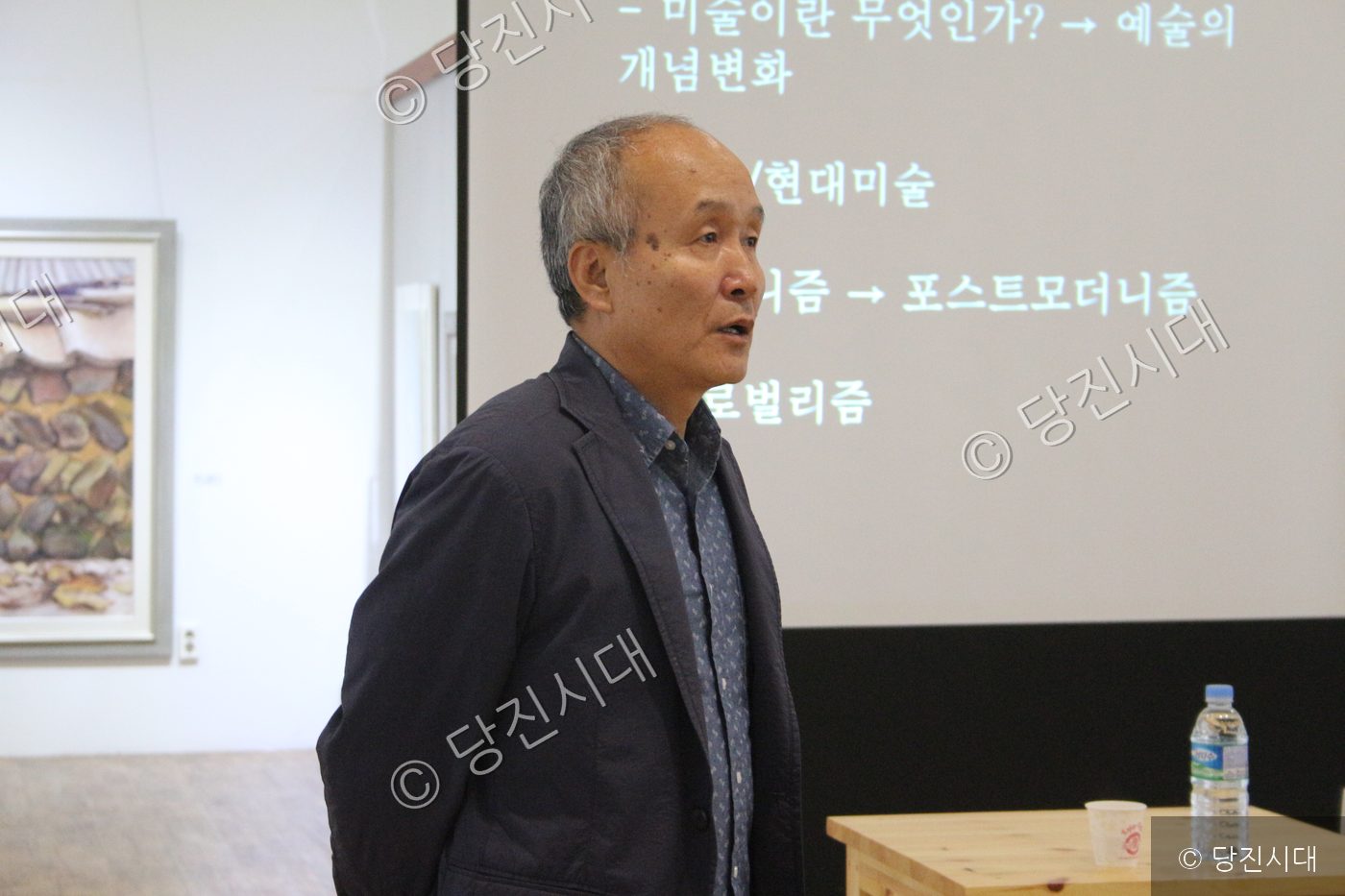 한 남성이 전시실에서 현대미술을 주제로 강의를 진행하고 있다.